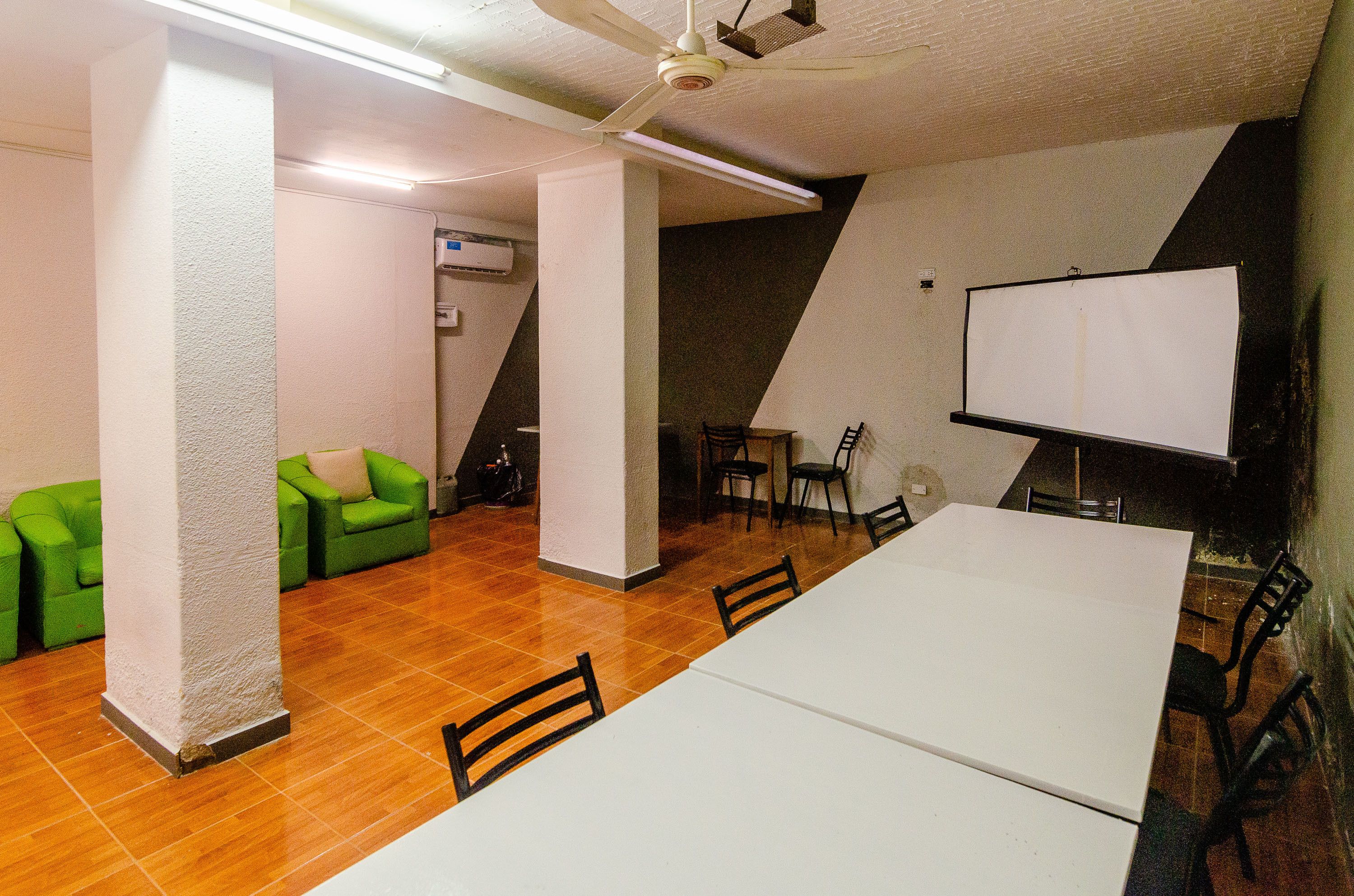 A conference room with a white table, chairs, a whiteboard, and green sofas.