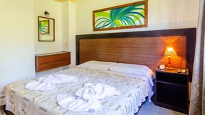 A neatly made bed with a patterned bedspread, a bedside lamp, and a nightstand with a phone. - Hotel Luz y Fuerza Villa Giardino (Villa Giardino)
