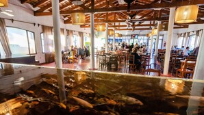 A restaurant with a koi pond, wooden tables, and a high ceiling with exposed beams. - Hotel Luz y Fuerza Villa Giardino (Villa Giardino)
