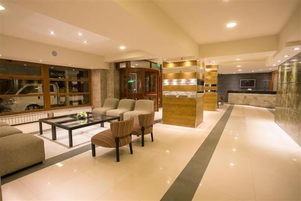A modern lobby with a reception desk, seating area, and a large window. - Hotel Aguas del Sur (San Carlos de Bariloche)