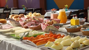 A buffet table with various breakfast items including bread, cheese, fruits, and beverages. - Pousada Vale da Montanha (Serra Negra)