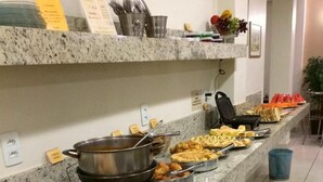 A buffet setup with various food items and utensils on a granite countertop. - Hotel Rio Branco (Goiania)