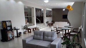 A modern living room with a grey sofa, a coffee machine, a small table, and a colorful rug. - Hotel Rio Branco (Goiania)
