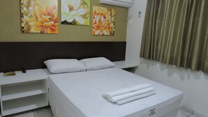 A hotel room with a bed, white pillows, a headboard, and three floral paintings on the wall. - Hotel Rio Branco (Goiania)