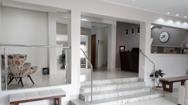 A modern interior with a staircase, a reception desk, and a seating area with a bench. - Hotel Rio Branco (Goiania)