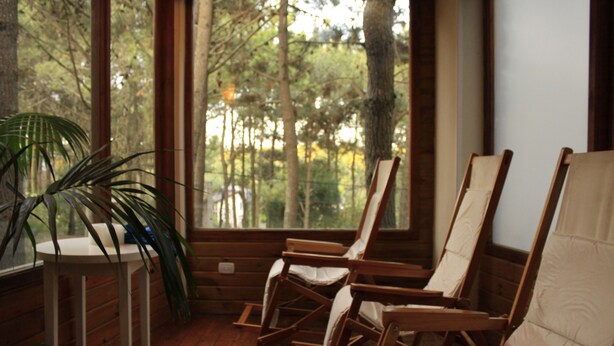 A room with wooden rocking chairs, a small table, and a potted plant.