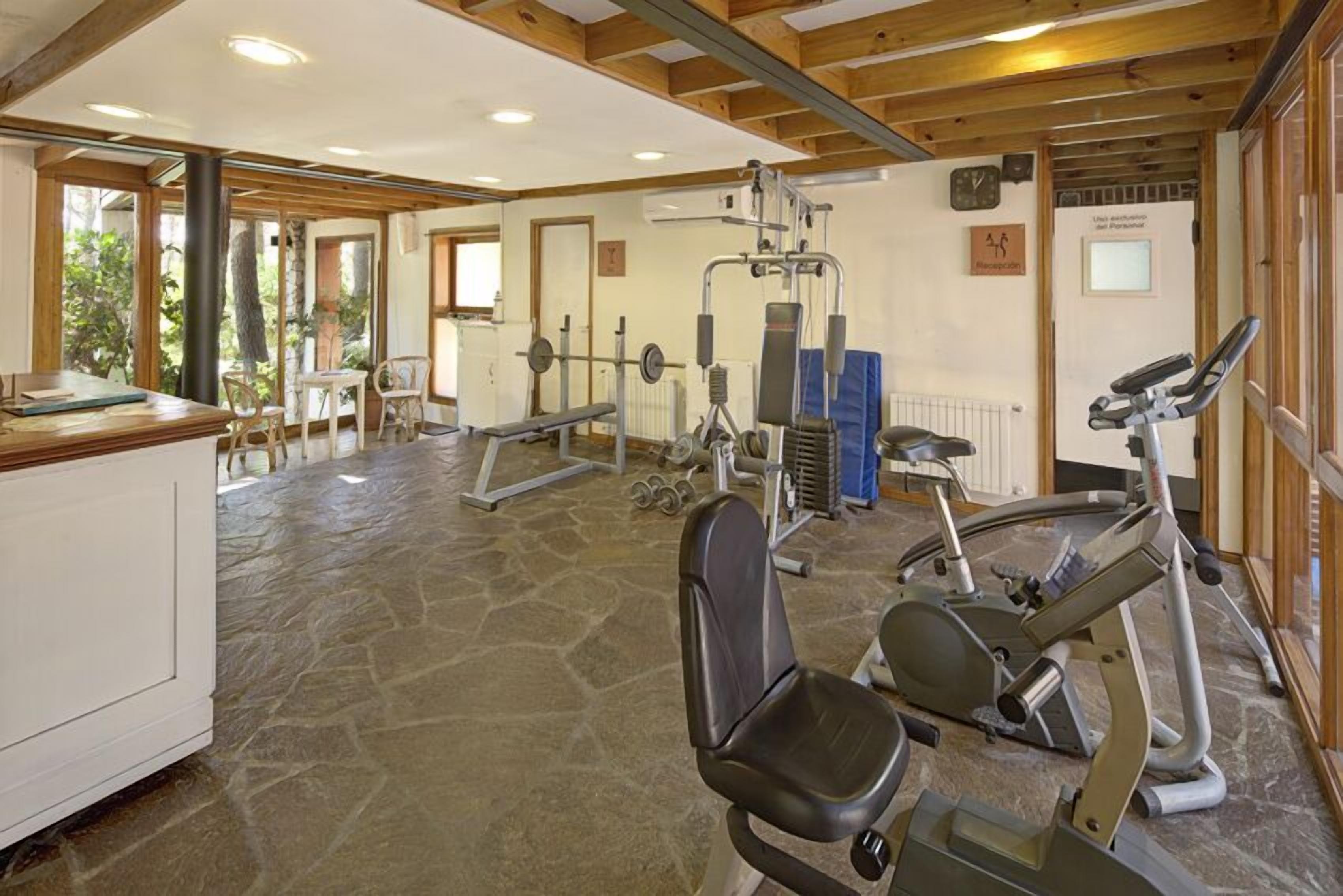 A gym with exercise equipment, a reception desk, and a stone floor.