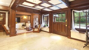 A spacious room with a high ceiling, large windows, and a fireplace.