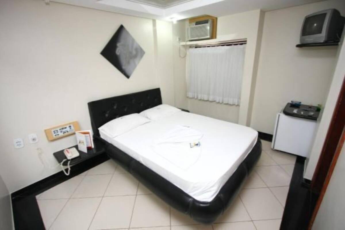 A hotel room with a bed, a small desk, a telephone, and a television.
