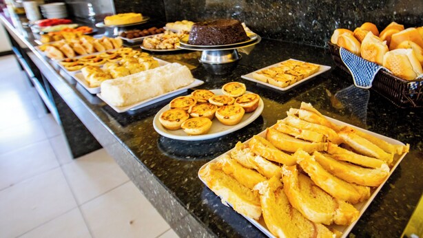 Un bufé con diversos alimentos, incluyendo pan, pasteles y un pastel.