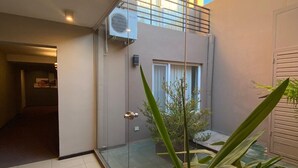 A modern building with a glass door, a visible air conditioning unit, and a potted plant. - Hotel Aires de Tandil (Tandil)