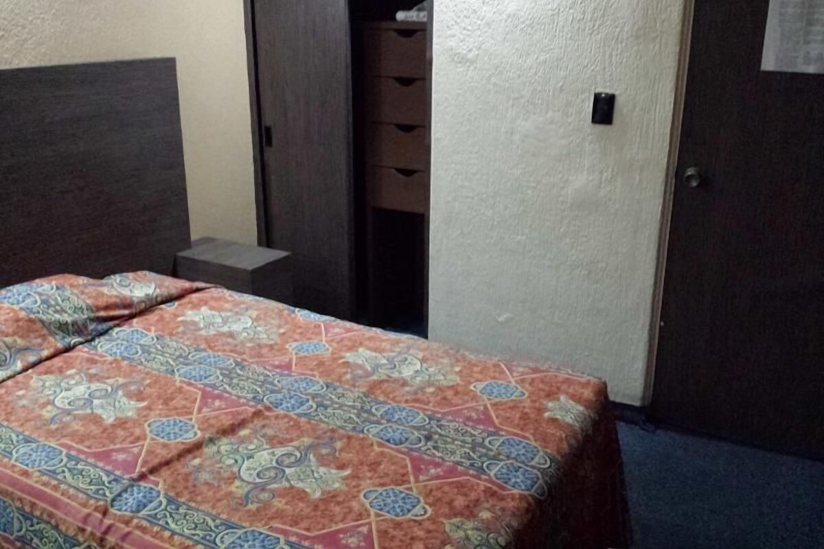 A hotel room with a bed, a wardrobe, and a door.