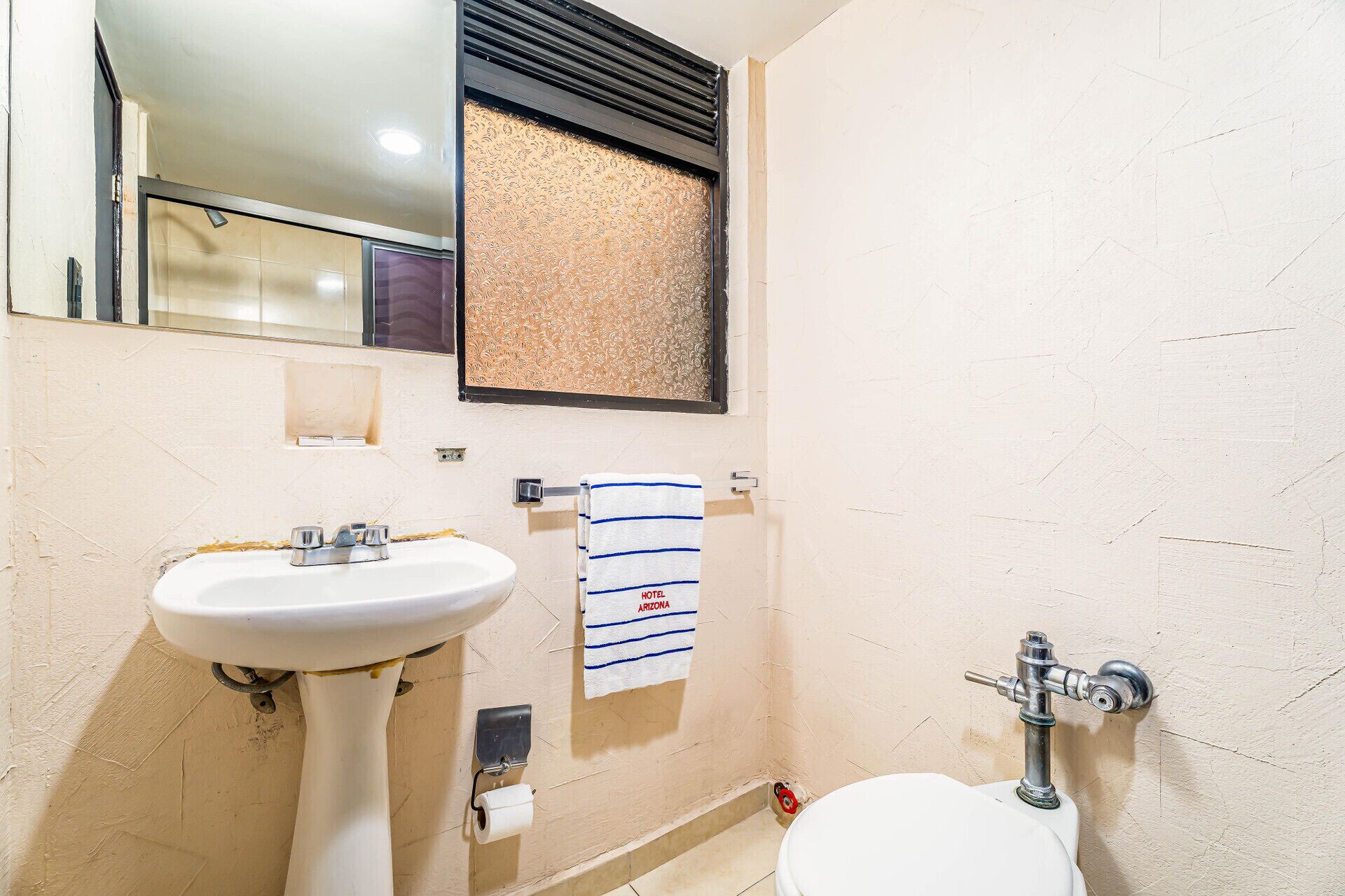 Un baño con lavamanos, inodoro y una toalla colgada en la pared.