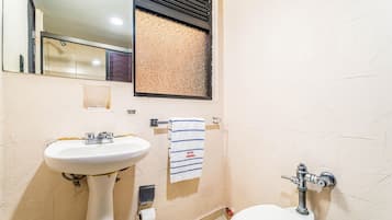 Un baño con lavamanos, inodoro y una toalla colgada en la pared.
