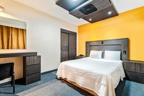 A hotel room with a bed, a desk, a chair, a mirror, and a ceiling fan. - Hotel Arizona (Mexico City)