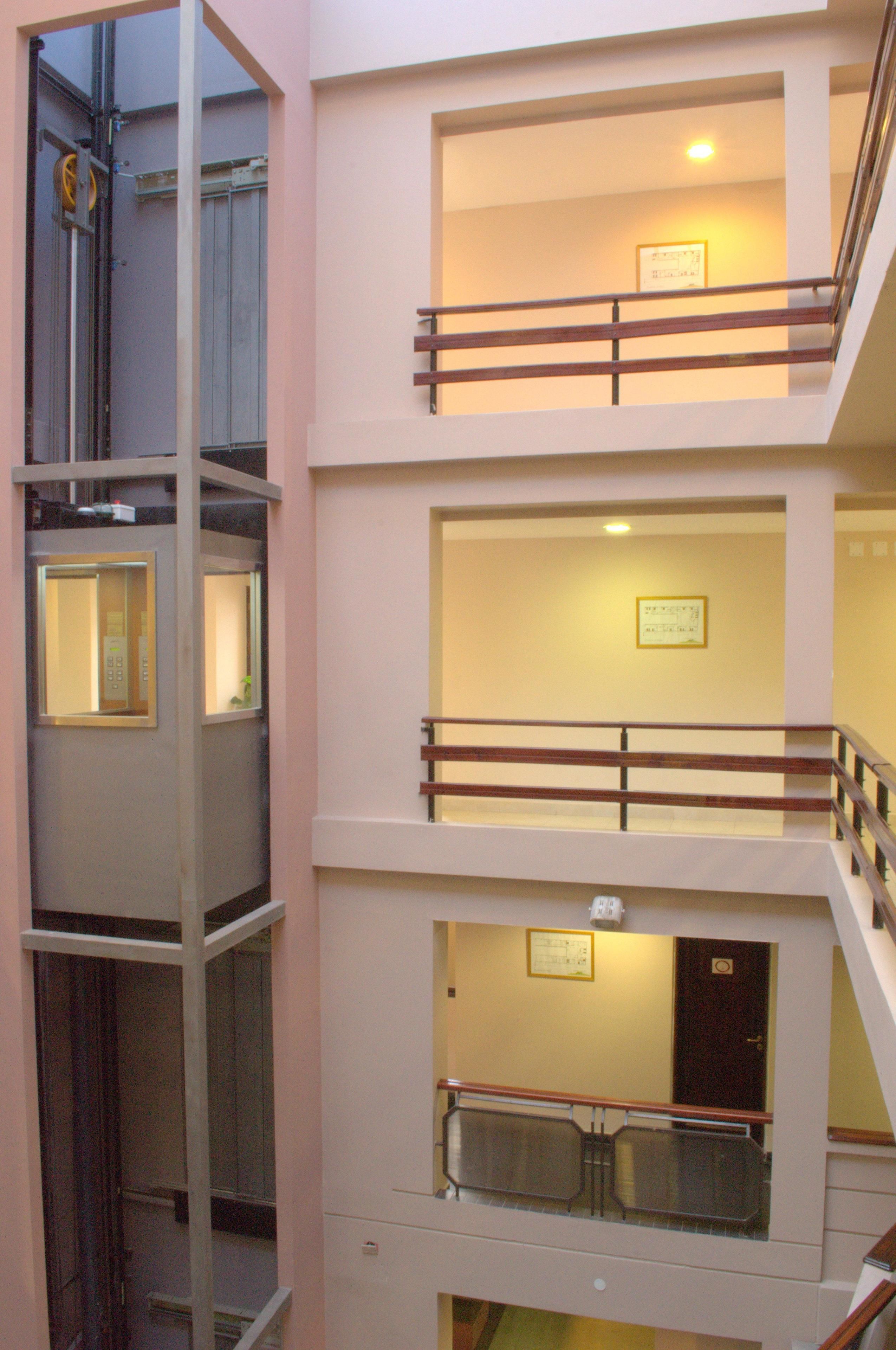 Un intérieur à plusieurs niveaux, doté d’un puits d’ascenseur central, de nombreux balcons et d’un escalier.