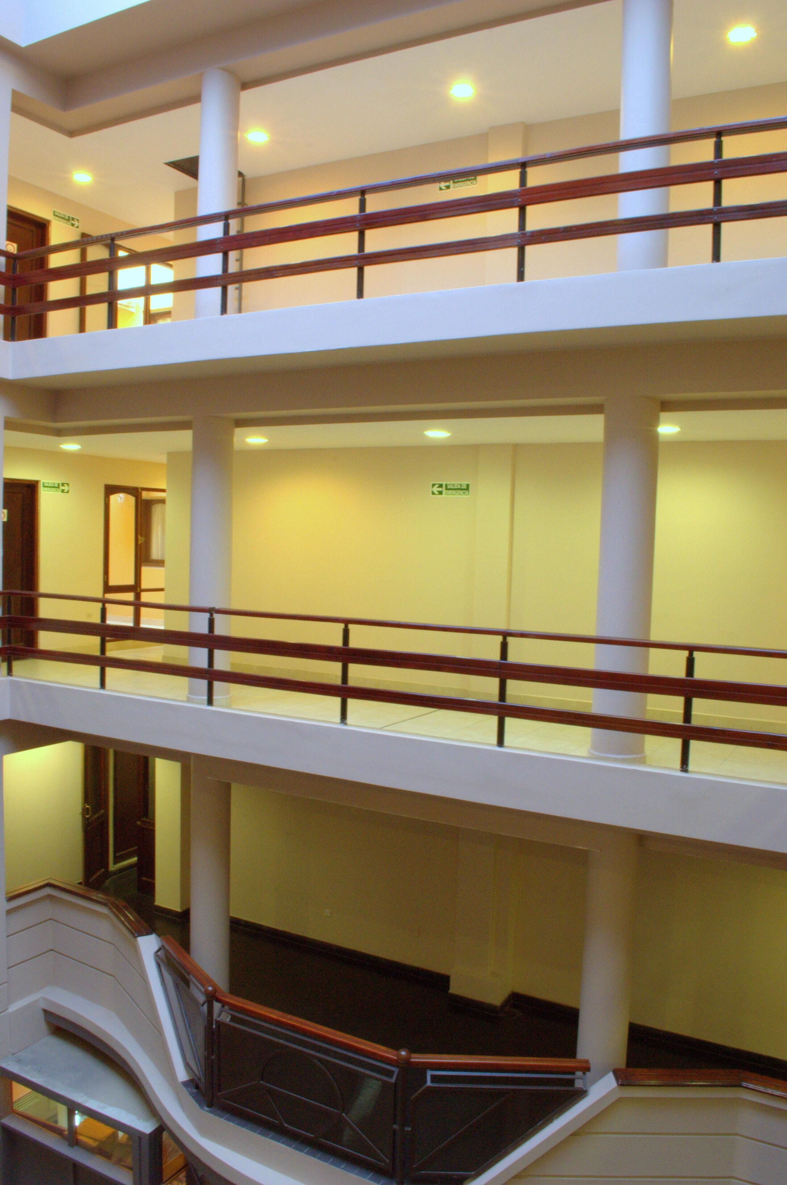 Un interno su più livelli con una scala centrale, pareti bianche e una ringhiera in legno.