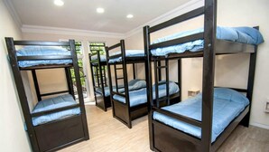 A dormitory room with bunk beds, wooden flooring, and a window with a view of greenery. - Jaque Mate Hostel (Mendoza)