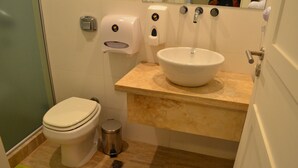 A bathroom with a toilet, a sink, a trash bin, and a hand dryer. - Jaque Mate Hostel (Mendoza)