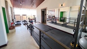 A gym with exercise equipment, a mirror, and a wooden ceiling. - Terrazzo hotel Campos dos Goytacazes (Campos)