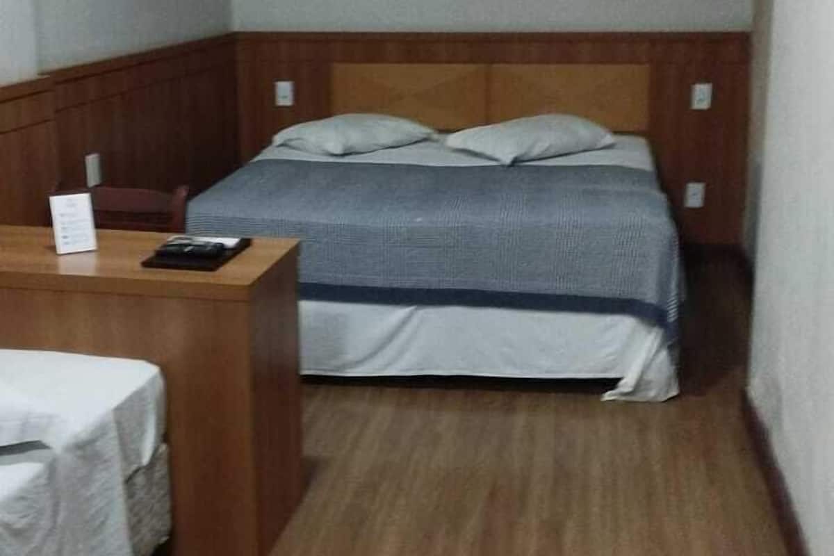 Una habitación pequeña y funcional con una cama individual, un escritorio y una silla.