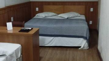 A small, compact room with a single bed, a desk, and a chair.