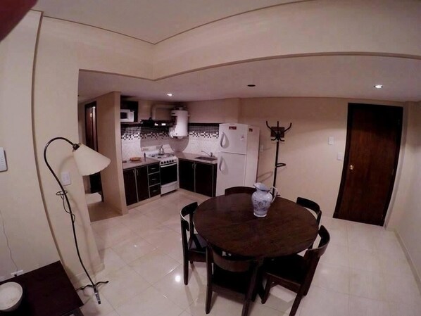 A compact kitchen with a dining table, a microwave, a stove, and a refrigerator.