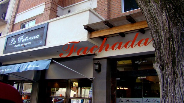 A building with a sign for "La Patrona Parrilla-Restaurant" and another sign for "Fachada."