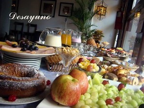 A breakfast buffet with various fruits, pastries, and beverages.