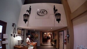 A hotel lobby with a reception desk, a clock, and a sign with the hotel's initials. - Apart Hotel Della Riviera (San Bernardo del Tuyú)