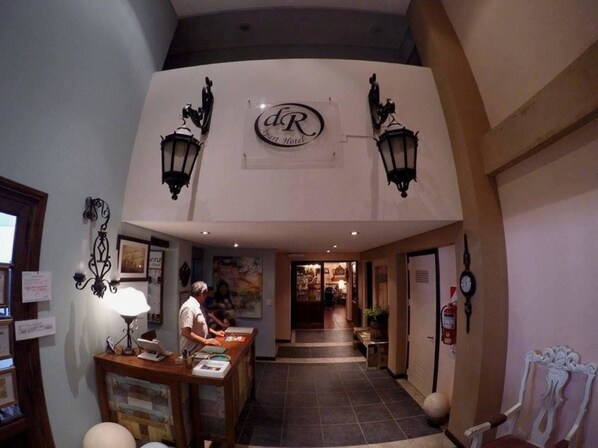 A hotel lobby with a reception desk, a clock, and a sign with the hotel's initials. - Apart Hotel Della Riviera (San Bernardo del Tuyú)