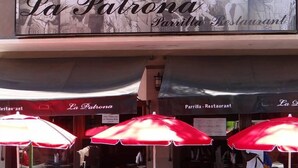 An outdoor seating area of La Patrona restaurant with red umbrellas and tables. - Apart Hotel Della Riviera (San Bernardo del Tuyú)