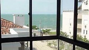 A view from a window with a clear view of the sea and a street.
