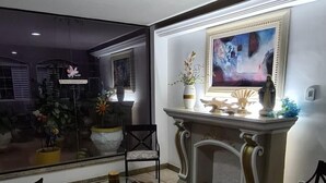 Un salón acogedor con chimenea, una mesa de centro, dos sillones y un ventanal con vistas al exterior.