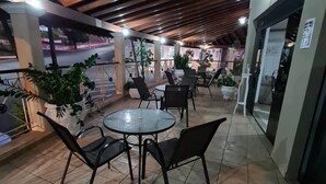 Un patio al aire libre con una mesa redonda y sillas, plantas en macetas y vista a la calle.