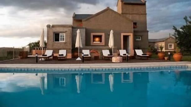 Un edificio grande con piscina, mobiliario exterior y chimenea.