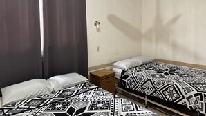 A small, simple room with two beds, a nightstand, a wall-mounted light, and a ceiling fan. - Hotel Morales Inn (Mazatlán)