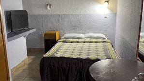 A room with a bed, a small table, a television on a stand, and a wall-mounted light fixture. - Hotel Morales Inn (Mazatlán)