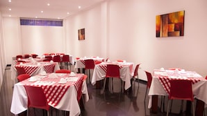 A dining area with multiple tables set with white tablecloths and red chairs, arranged in rows. - Hotel Dorado Gold Prime (Bogota)