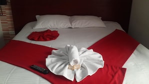 A neatly made bed with a red blanket, a white towel, and a remote control on the bed. - Hotel Dorado Gold Prime (Bogota)