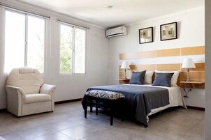 Una habitación de hotel con una cama, una silla y dos ventanas.