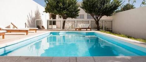A swimming pool with lounge chairs and a small deck area.