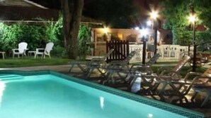 En swimmingpool med liggestole og et overdækket område med stole og borde.