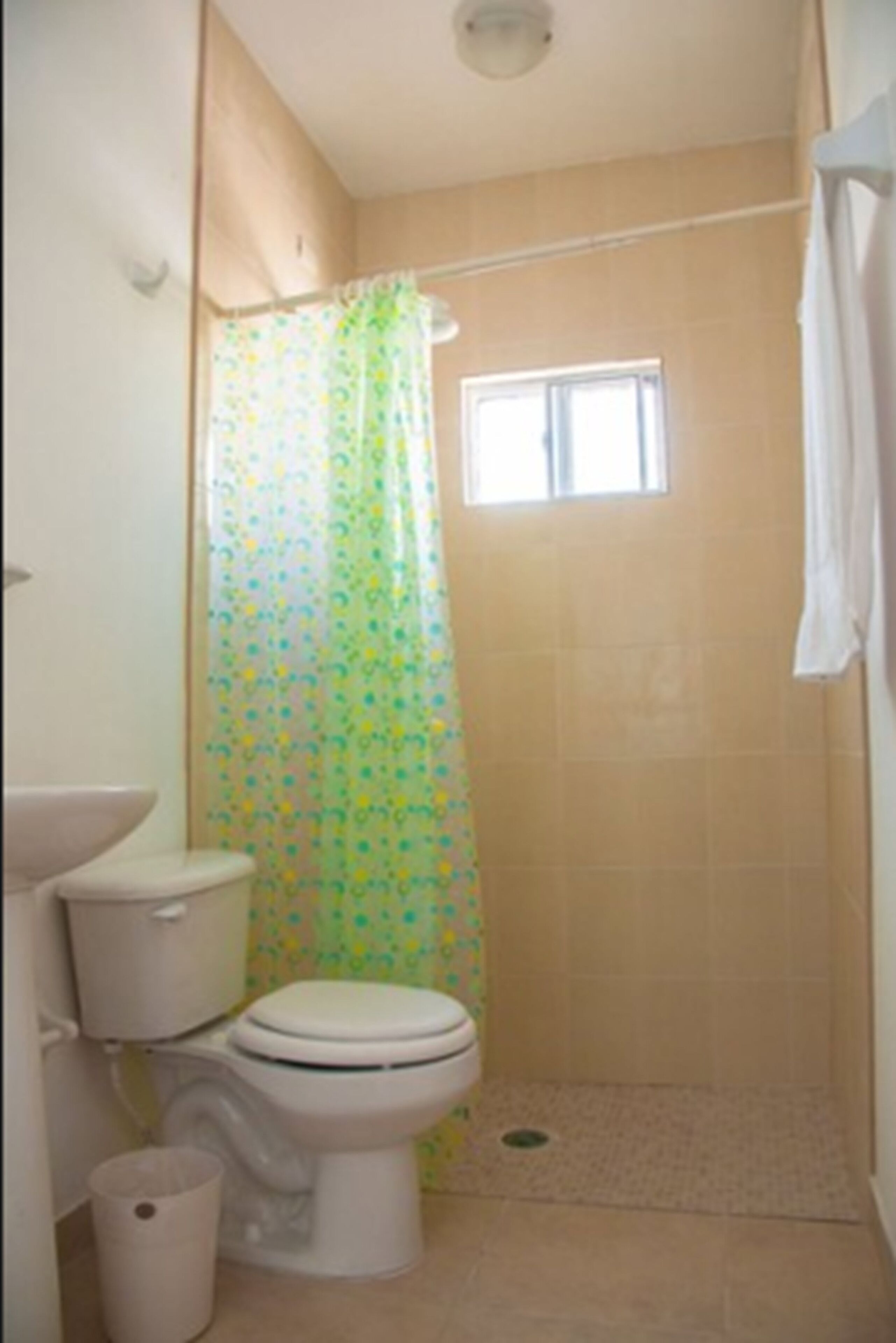Un baño pequeño con inodoro, cortina de ducha y ventana.