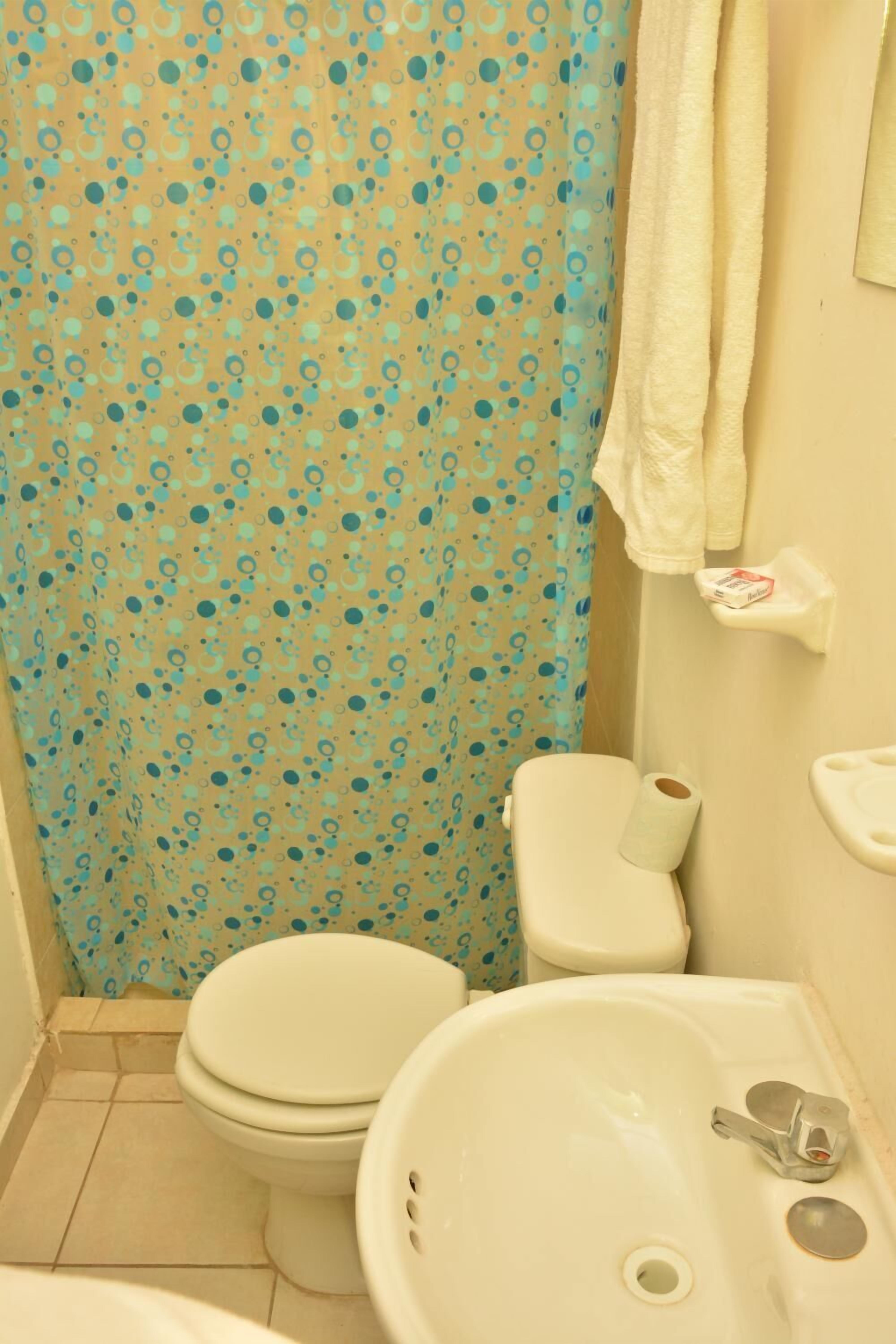 Un baño con inodoro, lavamanos y cortina de ducha.