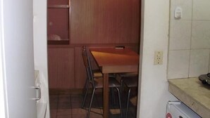 A compact kitchen with a wooden table and chairs, a tiled backsplash, and a small countertop. - Serú Apartments (Mendoza)