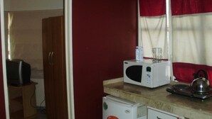 A compact kitchen with a microwave, kettle, and a small refrigerator. - Serú Apartments (Mendoza)