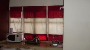 A kitchen with a microwave, kettle, and sink. - Serú Apartments (Mendoza)