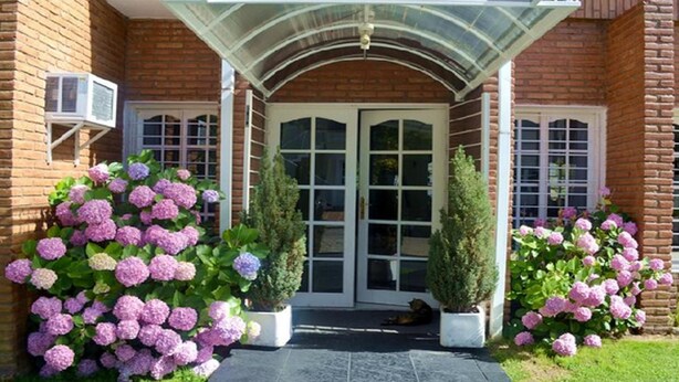 A brick building with a glass entryway, two potted plants, and a door with glass panels. - Hotel Casablanca Mina Clavero (Mina Clavero)