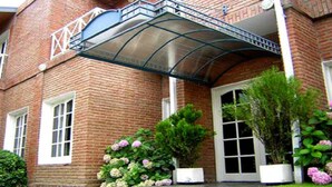 A brick building with a covered balcony, a large window, and potted plants with flowers. - Hotel Casablanca Mina Clavero (Mina Clavero)